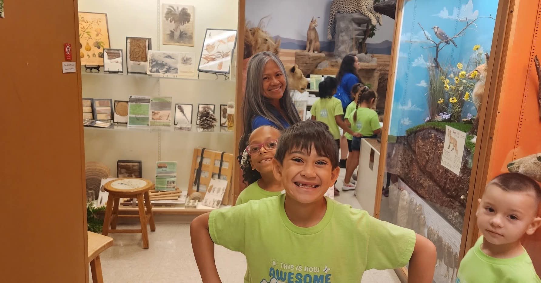 An adult with campers during a group museum visit