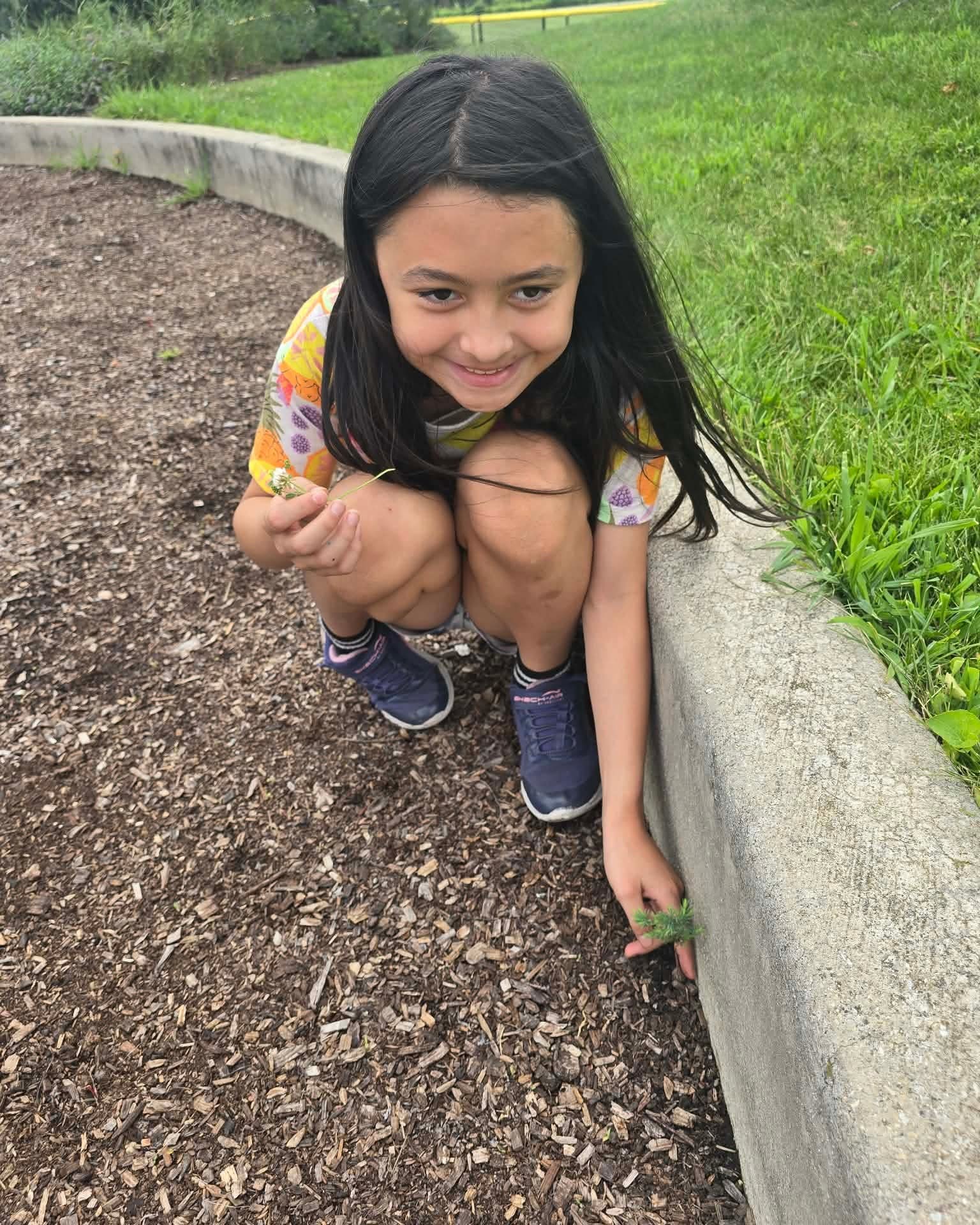 A camper crouching beside a garden bed outdoors